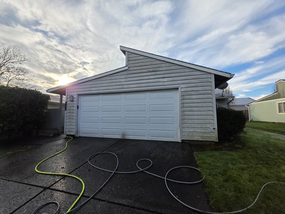 Pressure washing hoses laid out on a driveway before a house wash